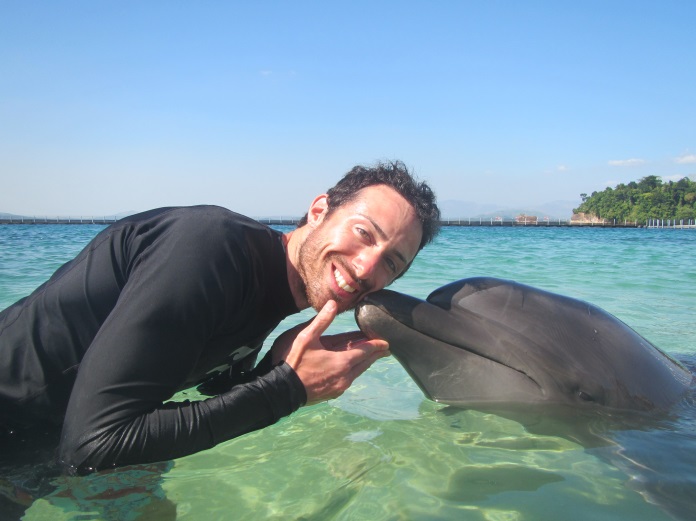 A smiling dolphin kisses a guy.